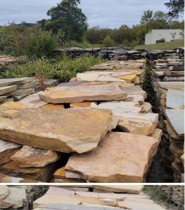 Flat irregular sandstone slabs stacked in tan and pink at the yard