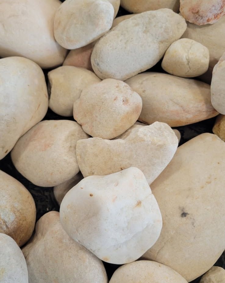 A close view of smooth light beige and white river pebbles