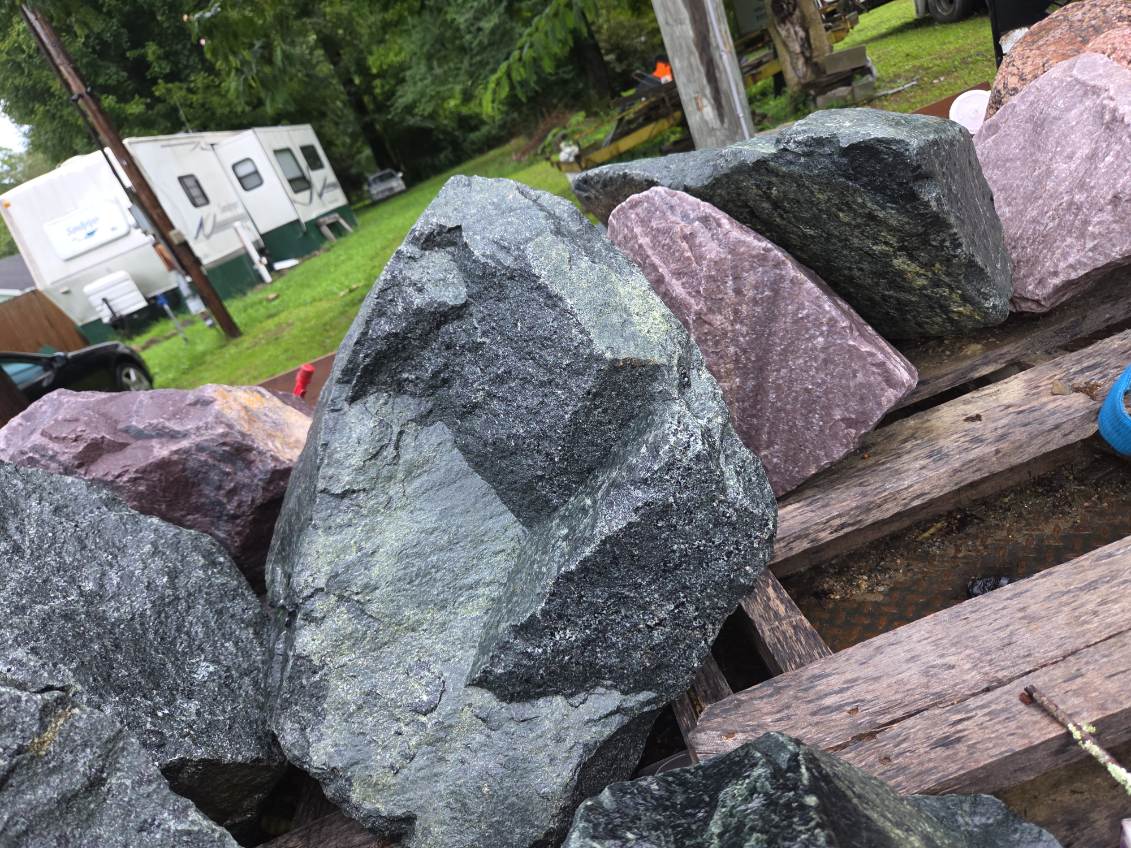 Dark green, grey and purple boulders laid out on weathered wooden planks